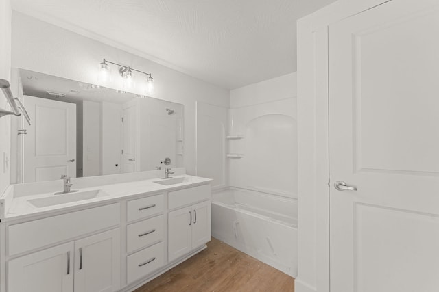 bathroom featuring a textured ceiling,  shower combination, hardwood / wood-style floors, and vanity