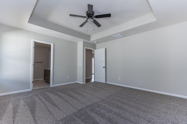 unfurnished bedroom featuring carpet, ensuite bathroom, a raised ceiling, and ceiling fan