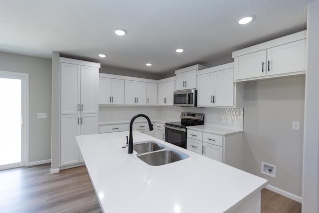 kitchen with stainless steel appliances, sink, a center island with sink, and white cabinets