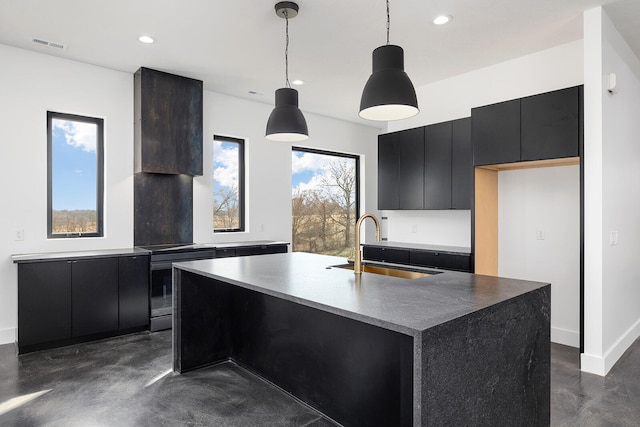 kitchen featuring a kitchen island with sink, sink, and decorative light fixtures