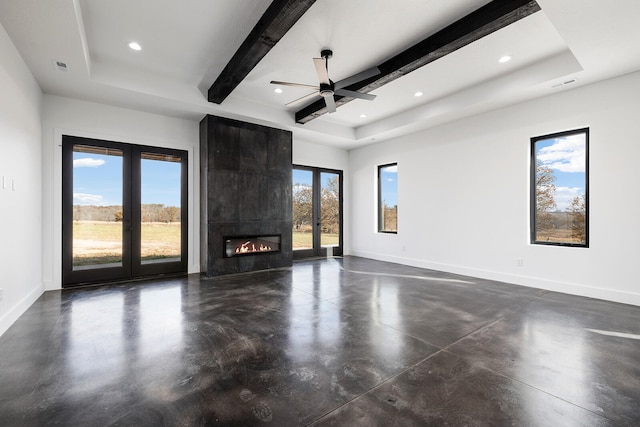 unfurnished living room with ceiling fan, beam ceiling, a fireplace, a raised ceiling, and french doors