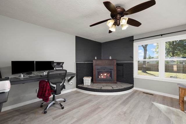 home office featuring light hardwood / wood-style flooring, a textured ceiling, and ceiling fan