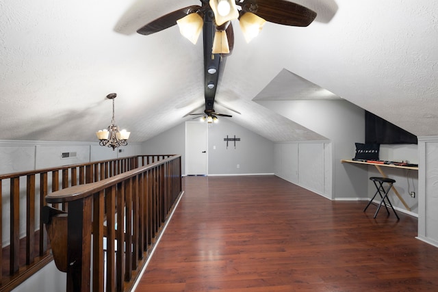 additional living space with a textured ceiling, vaulted ceiling, dark hardwood / wood-style floors, and ceiling fan with notable chandelier