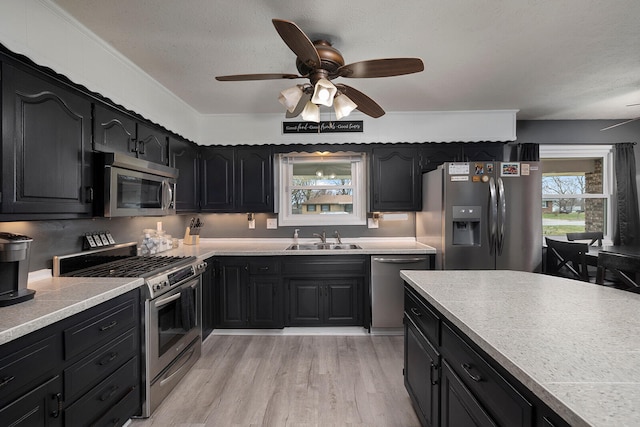 kitchen featuring sink, a textured ceiling, light hardwood / wood-style floors, stainless steel appliances, and ceiling fan