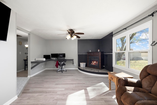 home office with light hardwood / wood-style floors and ceiling fan