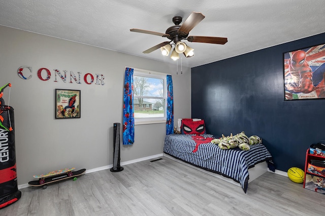 bedroom with ceiling fan, a textured ceiling, and light hardwood / wood-style flooring