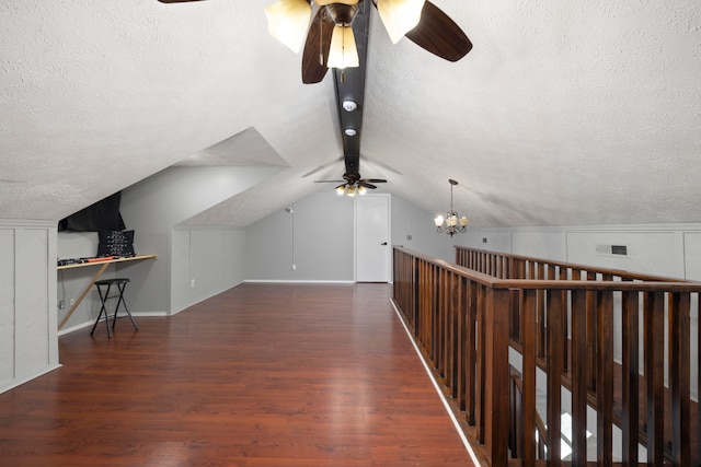 bonus room featuring lofted ceiling, dark hardwood / wood-style floors, a textured ceiling, and ceiling fan with notable chandelier