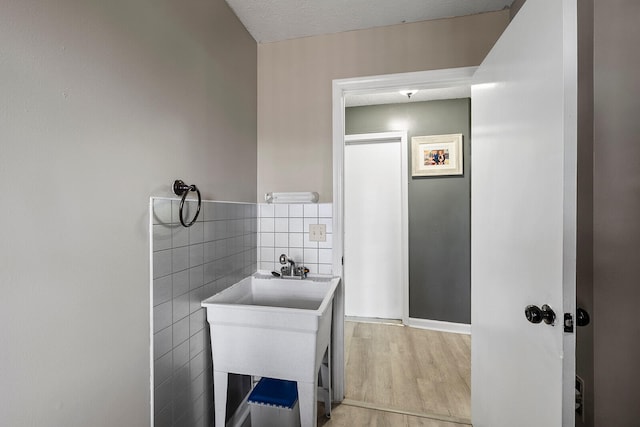 bathroom featuring hardwood / wood-style flooring, tile walls, and a textured ceiling