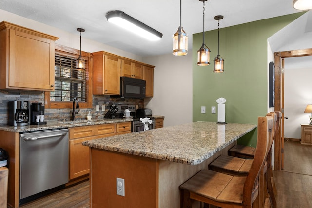 kitchen with tasteful backsplash, hanging light fixtures, light stone counters, dark hardwood / wood-style flooring, and stainless steel appliances