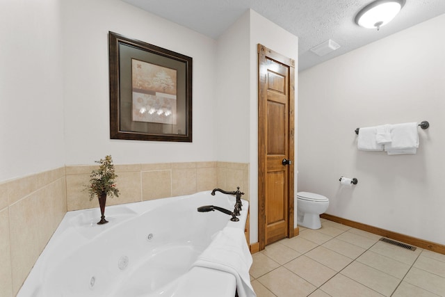 bathroom with tile patterned floors, a textured ceiling, toilet, and a bathing tub