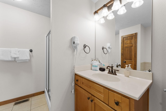 bathroom with vanity, a textured ceiling, a shower with shower door, and tile patterned floors