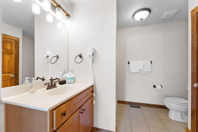 bathroom featuring vanity, a textured ceiling, toilet, and tile patterned floors