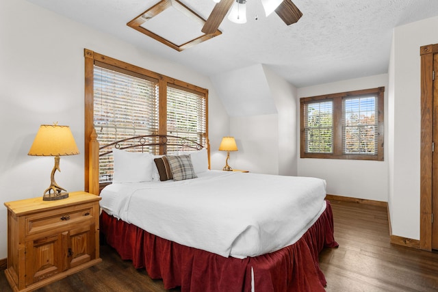 bedroom with ceiling fan, vaulted ceiling, multiple windows, and dark hardwood / wood-style floors