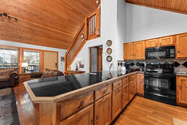 kitchen with high vaulted ceiling, black appliances, kitchen peninsula, and tile counters