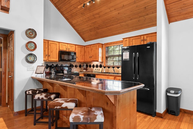 kitchen with light hardwood / wood-style floors, wood ceiling, kitchen peninsula, black appliances, and high vaulted ceiling