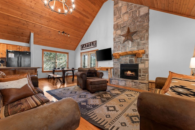 living room featuring a stone fireplace, high vaulted ceiling, wooden ceiling, and light wood-type flooring