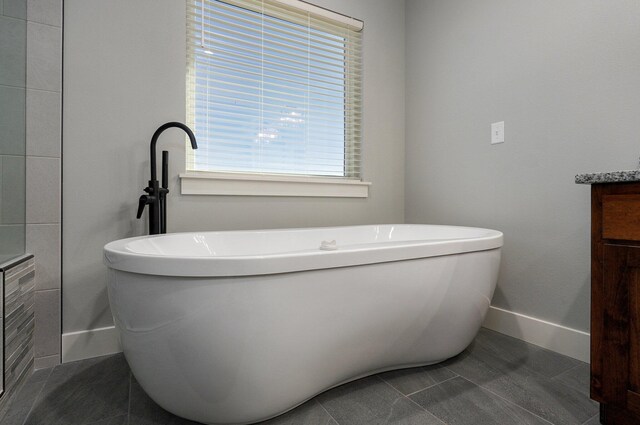 bathroom with vanity, a bath, a healthy amount of sunlight, and tile patterned floors