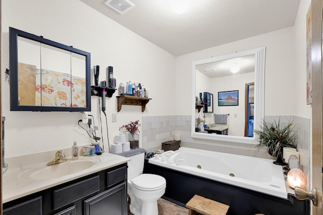 bathroom featuring vanity, a tub to relax in, toilet, and a textured ceiling