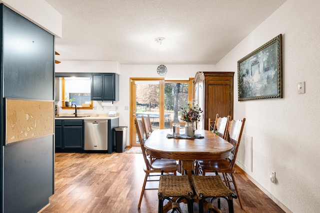 dining area featuring a textured ceiling, sink, and light wood-type flooring