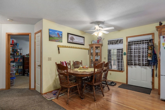 dining space with light hardwood / wood-style flooring, a textured ceiling, and ceiling fan