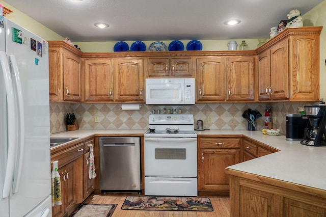 kitchen with backsplash, sink, light wood-type flooring, and white appliances