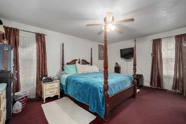 bedroom with ceiling fan, a textured ceiling, and dark carpet