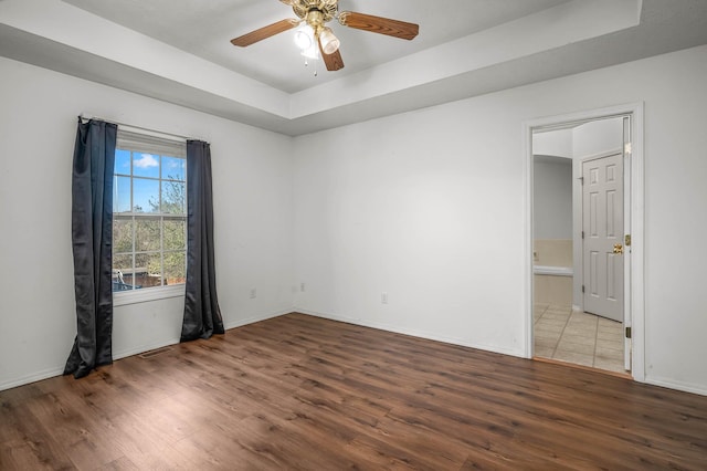 empty room featuring hardwood / wood-style flooring, a tray ceiling, and ceiling fan