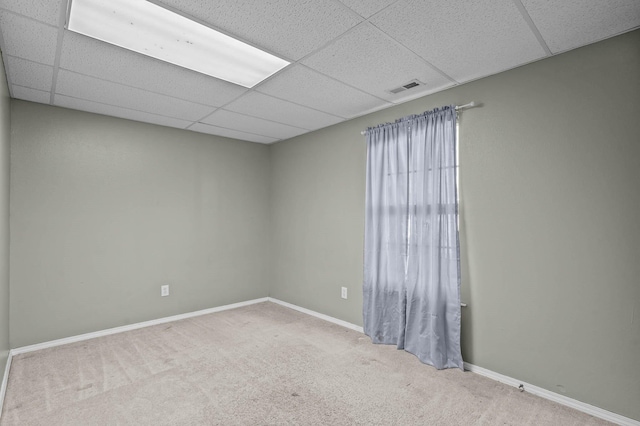 carpeted empty room featuring a paneled ceiling