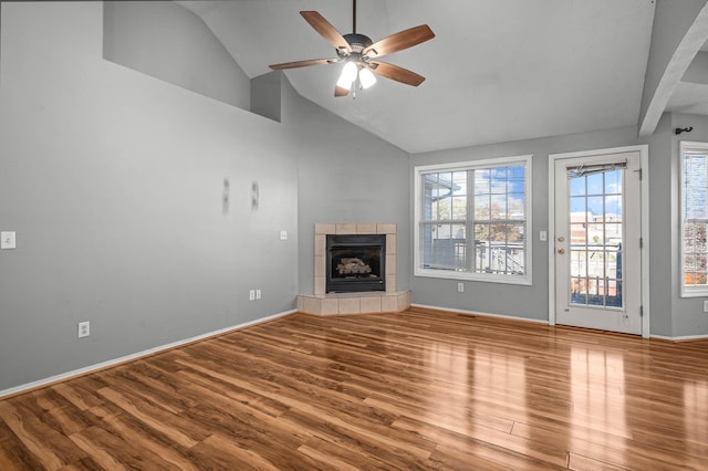 unfurnished living room with hardwood / wood-style floors, a tiled fireplace, high vaulted ceiling, and ceiling fan