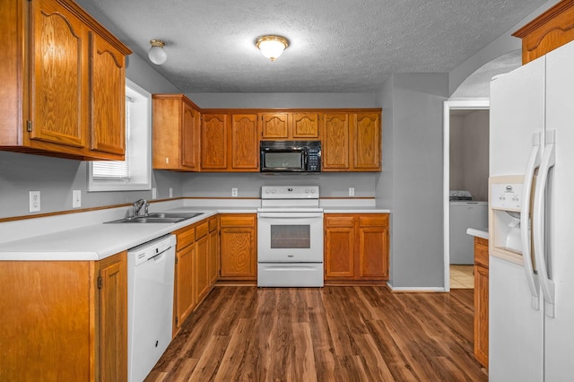 kitchen featuring white appliances, washer / dryer, sink, a textured ceiling, and dark wood-type flooring