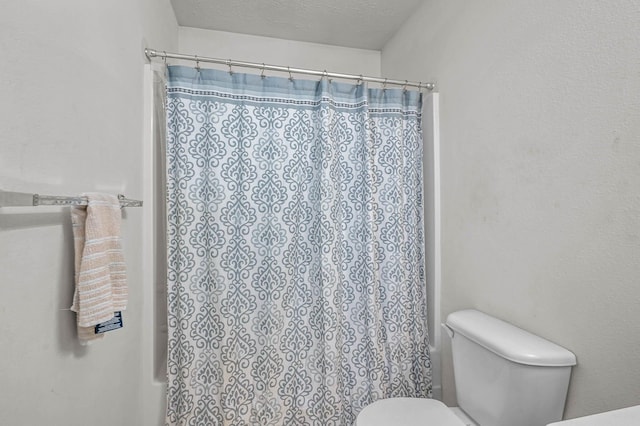 bathroom featuring toilet, a textured ceiling, and a shower with curtain