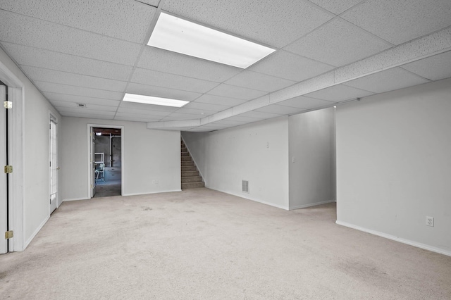 basement featuring a drop ceiling and light colored carpet