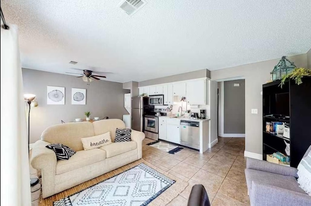 living room with sink, light tile patterned flooring, a textured ceiling, and ceiling fan