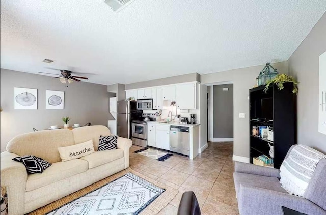 living room with ceiling fan, light tile patterned flooring, a textured ceiling, and sink