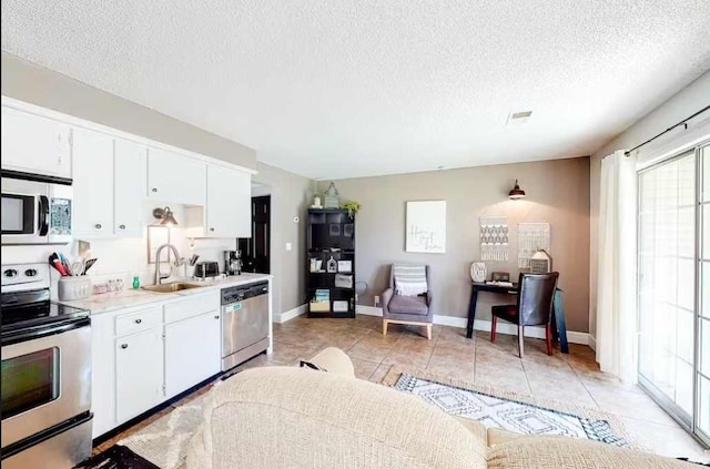 kitchen with white cabinetry, stainless steel appliances, sink, and a textured ceiling