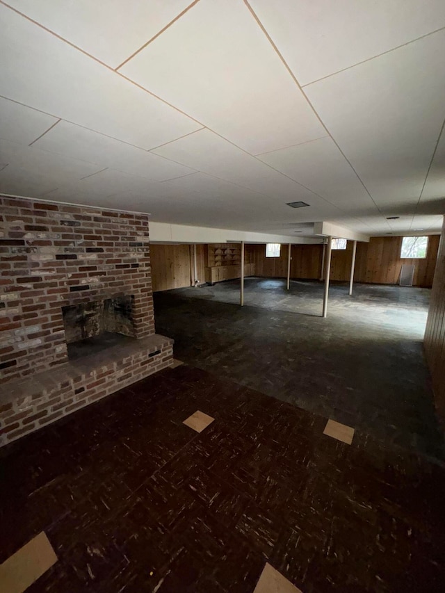 basement featuring wooden walls and a fireplace