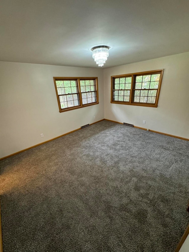 unfurnished room with a notable chandelier and carpet flooring