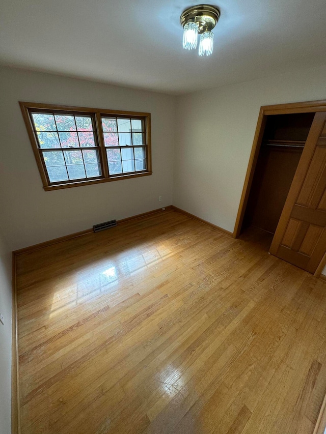 unfurnished bedroom featuring light hardwood / wood-style flooring and a closet