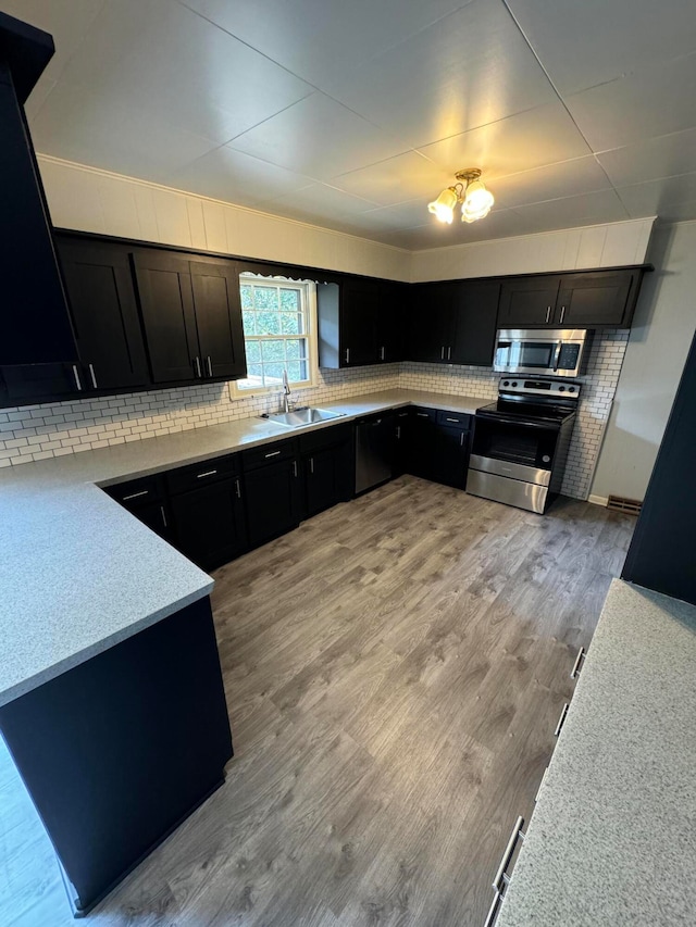 kitchen featuring light hardwood / wood-style floors, tasteful backsplash, appliances with stainless steel finishes, and sink