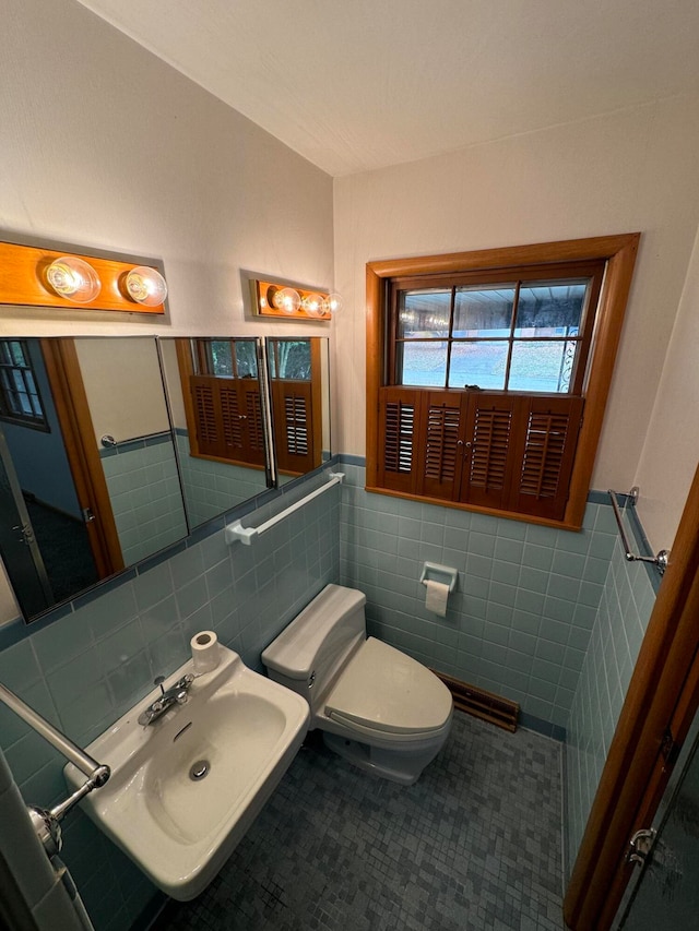 bathroom featuring toilet, tile walls, and sink