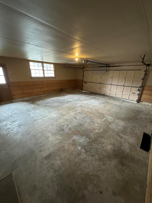 garage featuring a garage door opener and wooden walls