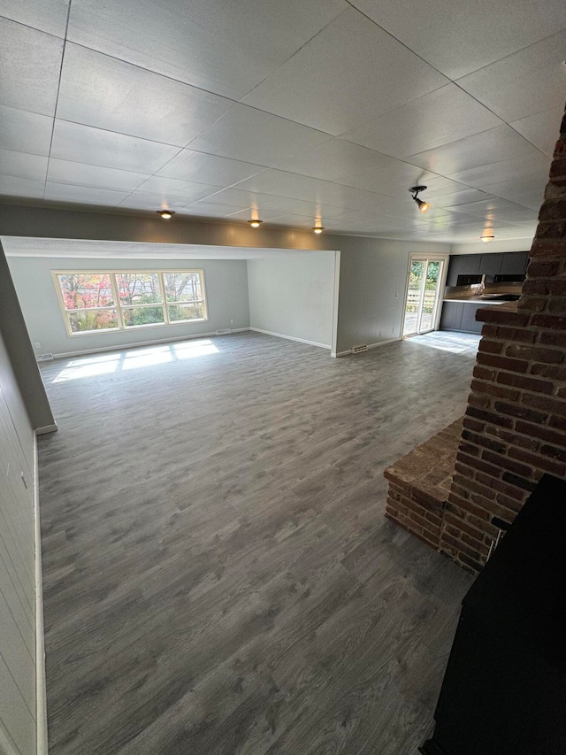 unfurnished living room with a paneled ceiling and dark hardwood / wood-style floors