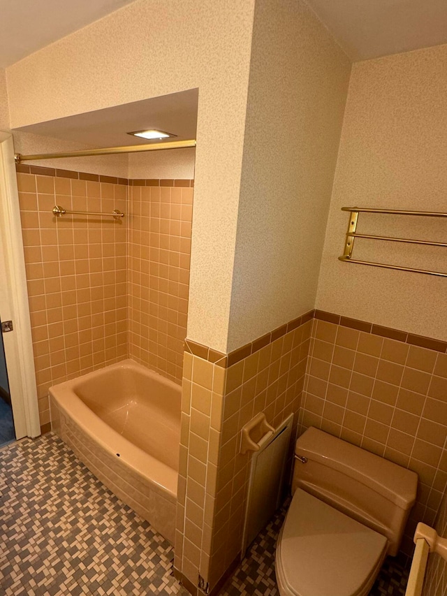 bathroom with toilet, radiator heating unit, and tile walls