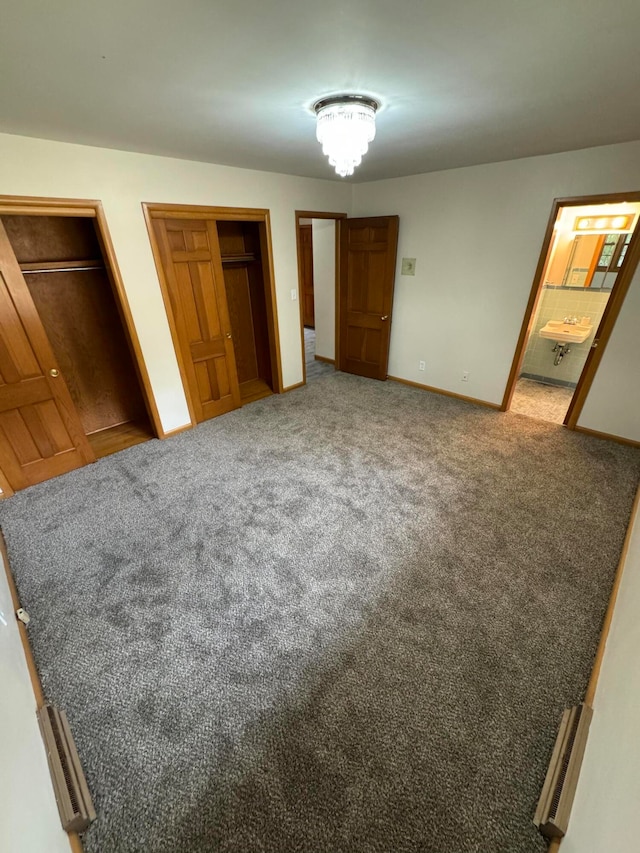 unfurnished bedroom featuring ensuite bath and carpet flooring