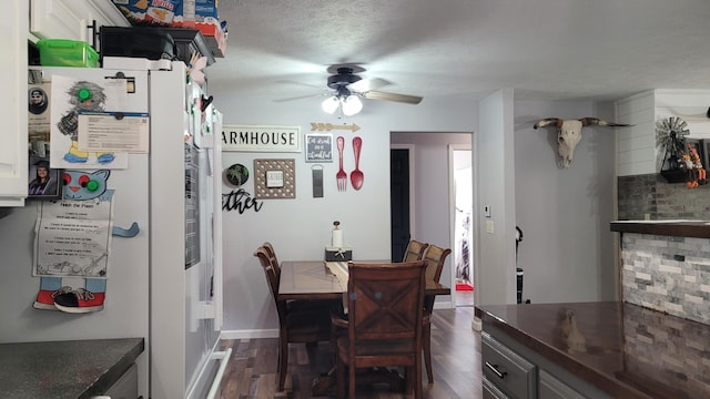 dining room featuring a textured ceiling, dark wood-type flooring, and ceiling fan