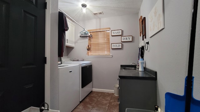 washroom with cabinets, washer and dryer, a textured ceiling, dark tile patterned floors, and sink