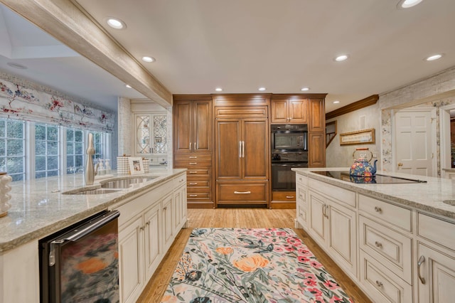 kitchen with light stone countertops, sink, black appliances, and light hardwood / wood-style floors