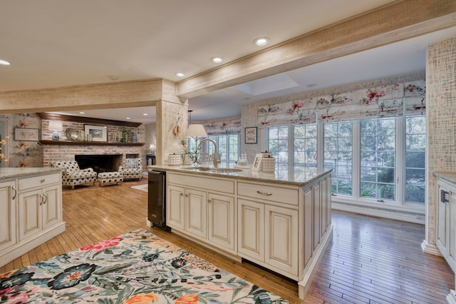 kitchen with a brick fireplace, light hardwood / wood-style floors, cream cabinets, and sink