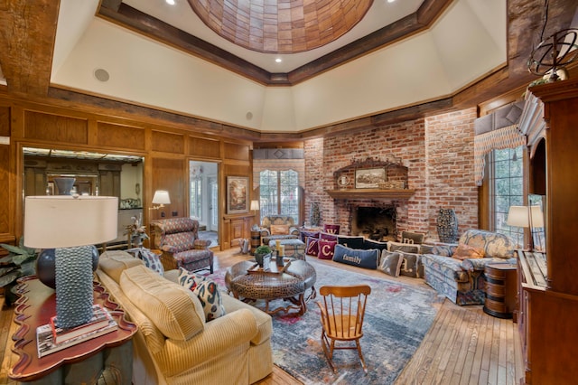 living room with wood walls, hardwood / wood-style flooring, a tray ceiling, a fireplace, and a towering ceiling