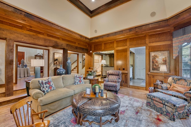 living room with wood walls, light wood-type flooring, and a towering ceiling